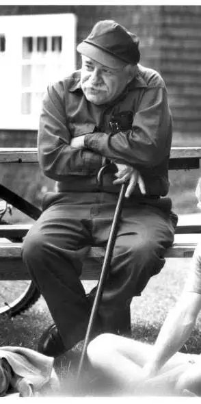 Murray Bookchin, late-life photograph, on a bench in coveralls and knit cap, with a cane